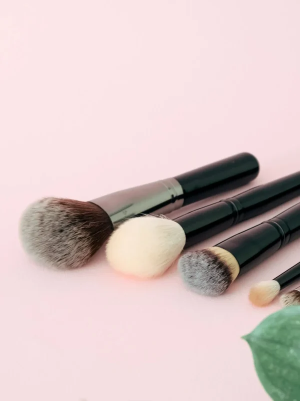 Real makeup brushes arranged on a pastel pink surface