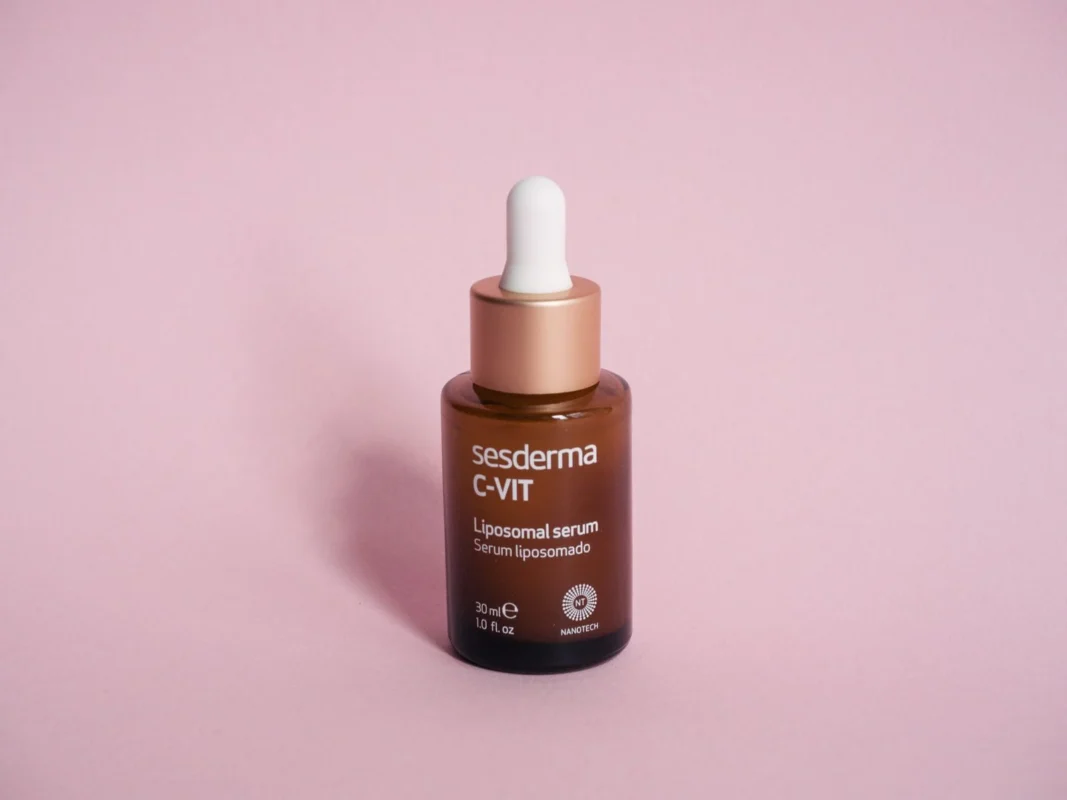 A real serum bottle photographed on a soft pink surface